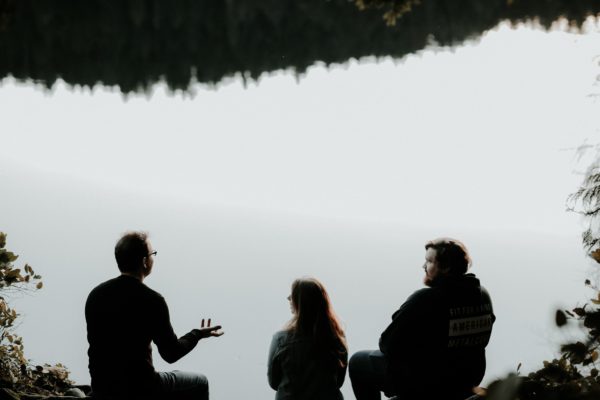 Three people collaborating by a lake